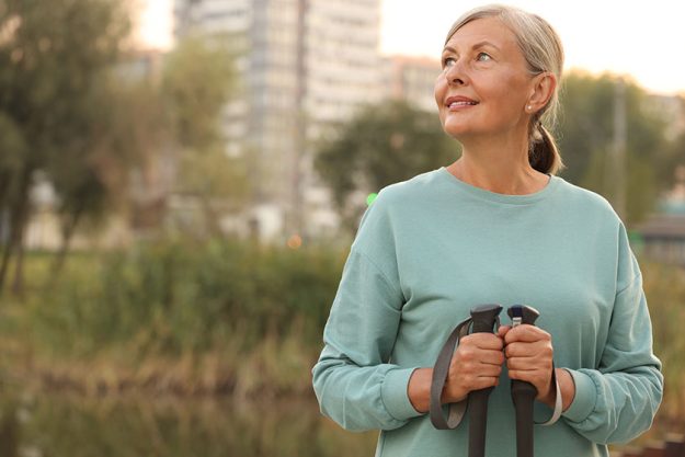Senior woman nordic walking poles outdoors space text Senior woman nordic walking poles outdoors space text