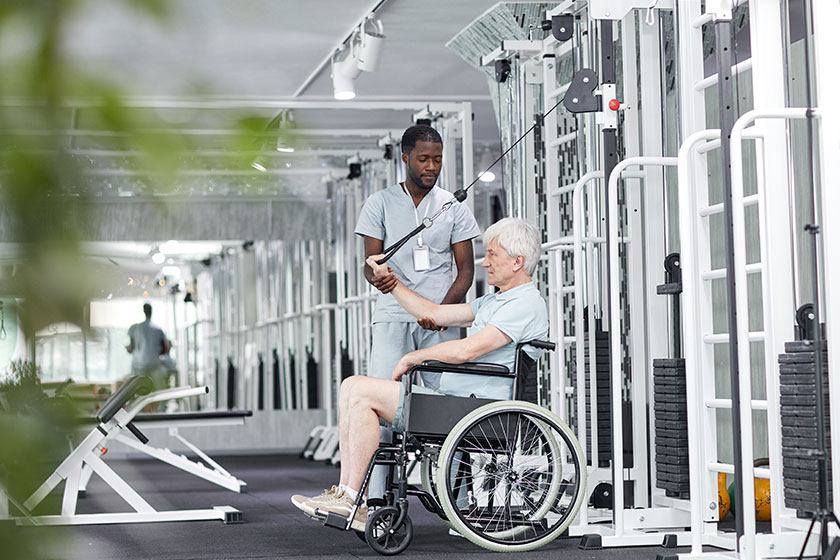 Side view portrait senior man wheelchair doing exercises gym rehabilitation