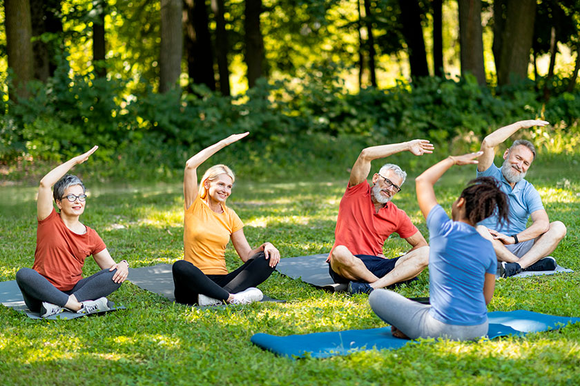 Sporty mature people doing stretching exercises group lesson instructor outdoors