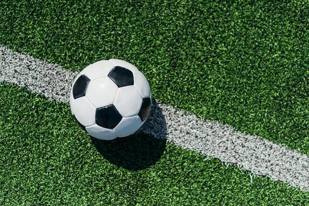 Top view of football ball on green grass with white line