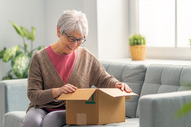 Beautiful senior woman is holding cardboard box Beautiful senior woman is holding cardboard box