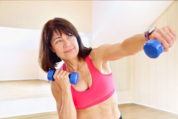 Fitness mature woman working out with dumbbell