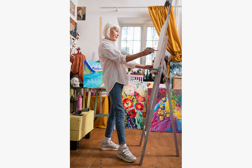 aged artist wearing jeans and sneakers painting in workshop aged artist wearing jeans and sneakers painting in workshop