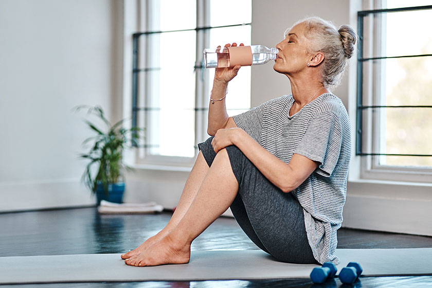 Bottoms mature woman practicing yoga while having drink water