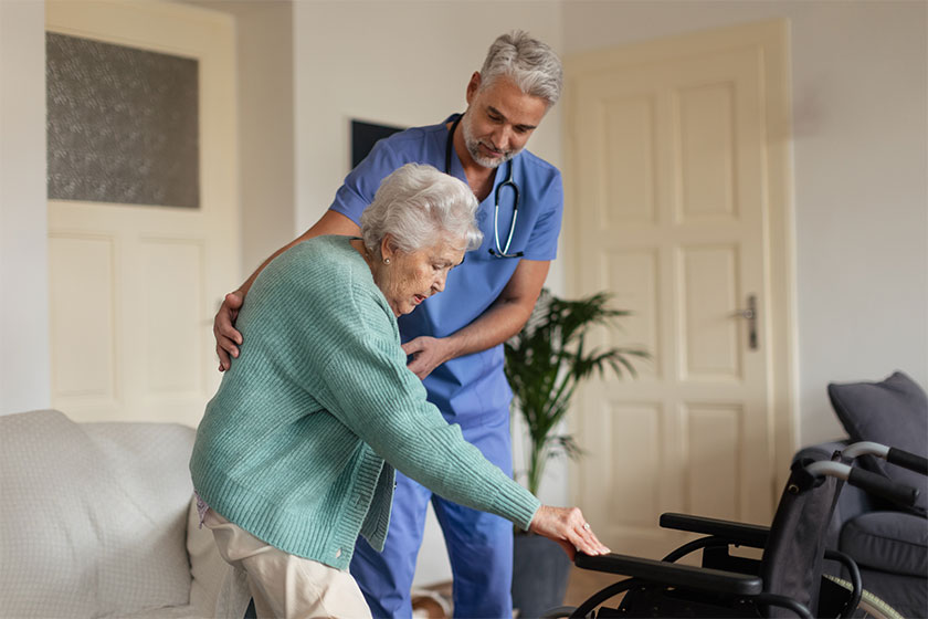 caregiver helping senior woman stand her wheelchair her home elderly