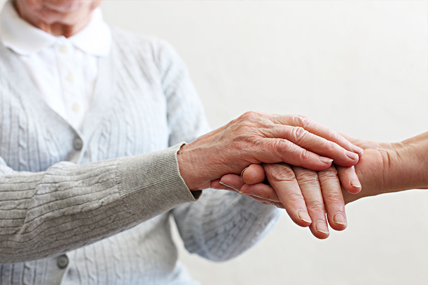close up shot of elderly womans hands old lady wearing grey knitted cardigan