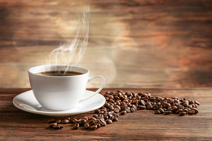 cup of coffee with grains on wooden background