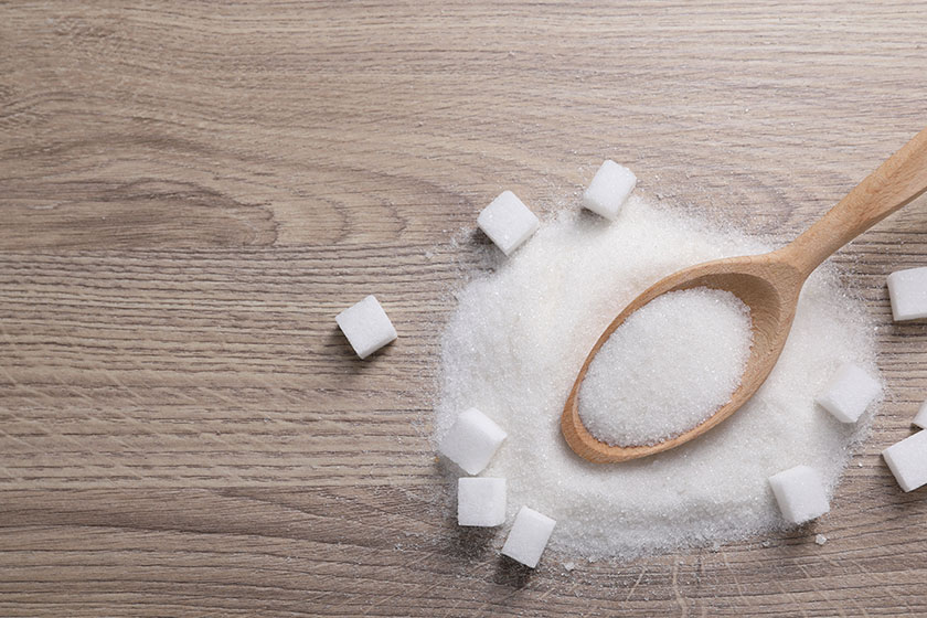 Different types white sugar spoon wooden table top view space