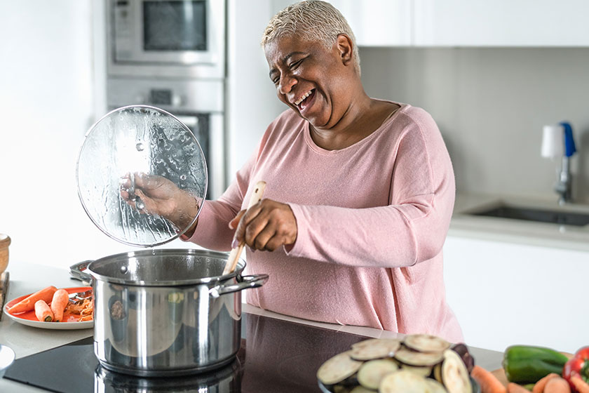 happy senior woman having fun preparing lunch modern kitchen hispanic