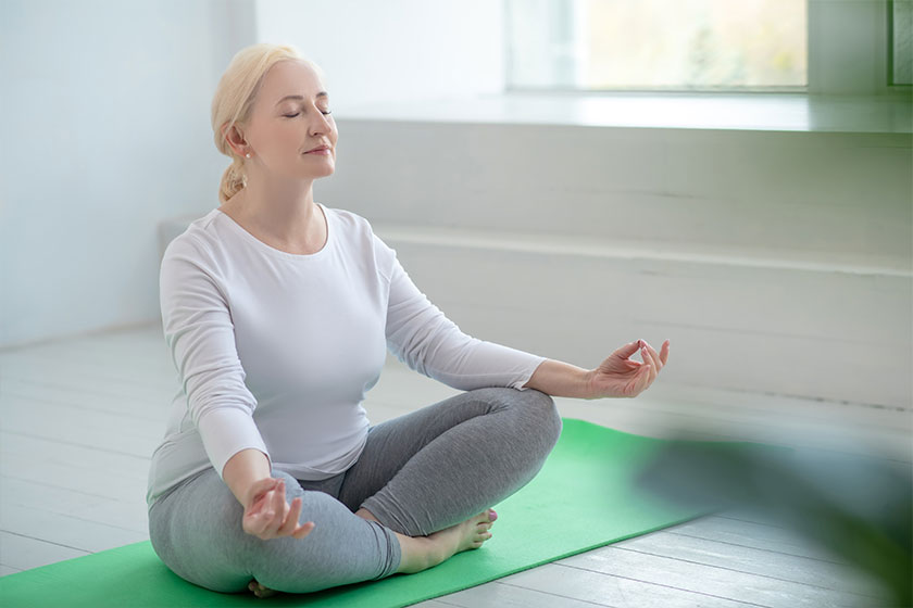 mature blonde female sitting in lotus pose meditating