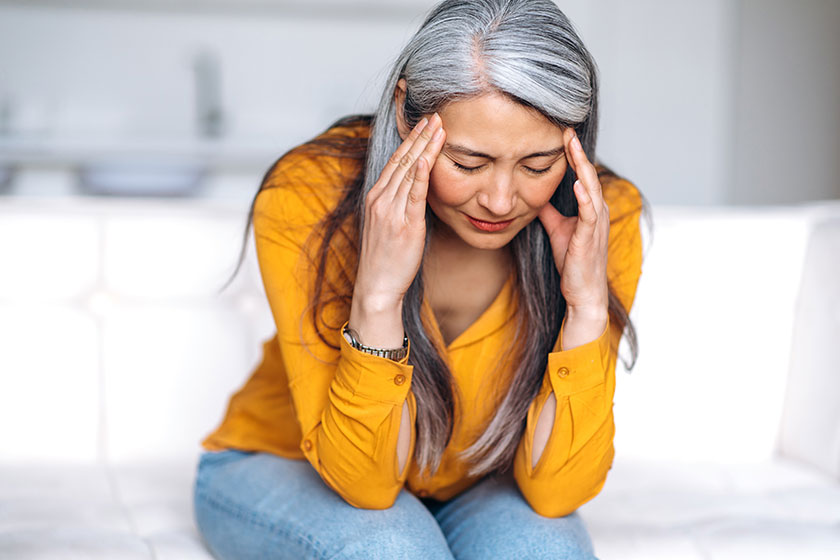 Middle aged gray haired asian woman sits couch living room