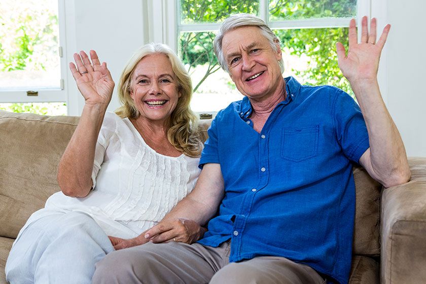 Senior couple waving hands while sitting