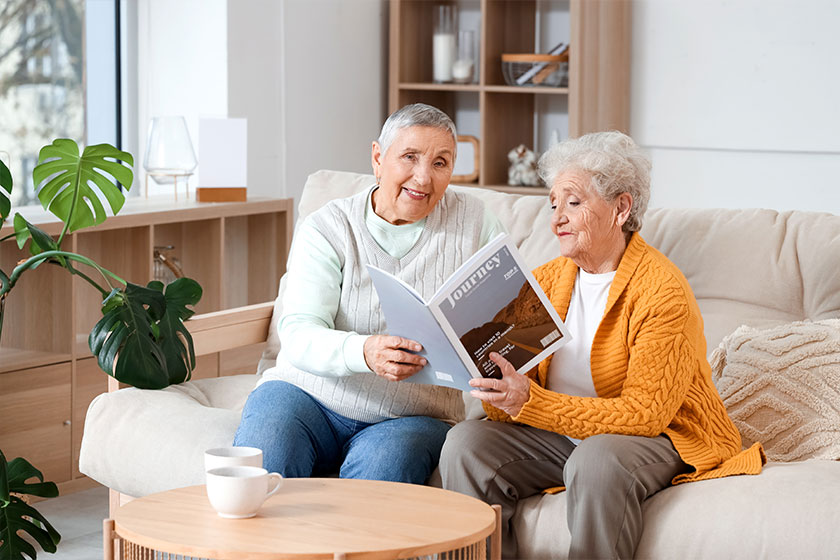 senior female friends reading magazine sofa home senior female friends reading magazine sofa home