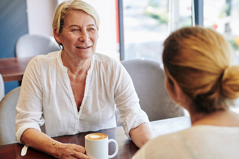 senior woman meeting her adult daughter cafe discuss news gossips