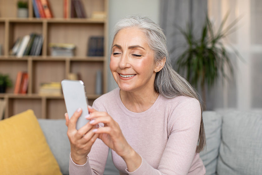 Smiling caucasian old gray haired female typing smartphone have online
