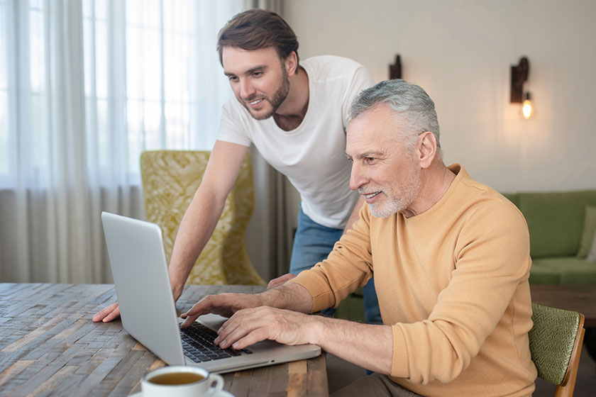 two men in the room at the laptop watching something on a laptop