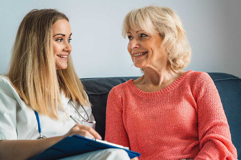 Young blonde woman caregiver helping senior woman home nurse assisting Young blonde woman caregiver helping senior woman home nurse assisting