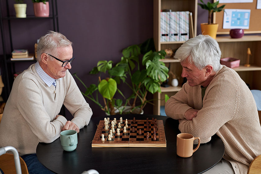 side view portrait two elderly men playing chess table retirement
