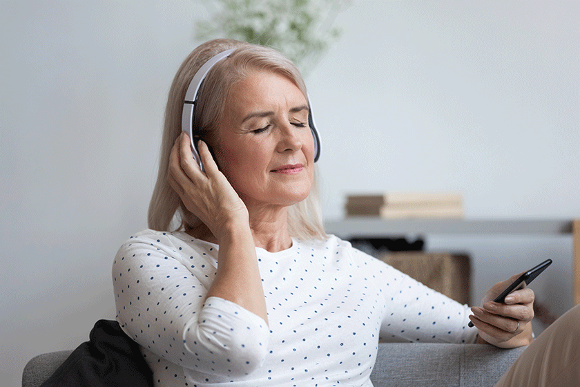 aged woman wearing headphones holding smartphone listens music online aged woman wearing headphones holding smartphone listens music online
