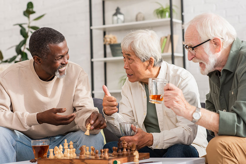 Asian man holding tea showing sign multiethnic friends chess home