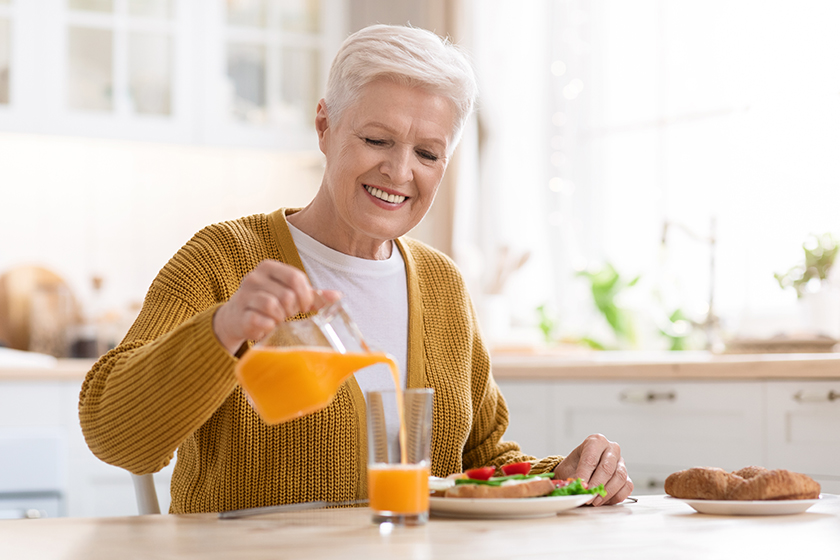 attractive grandmother pouring juice having lunch in kitchen