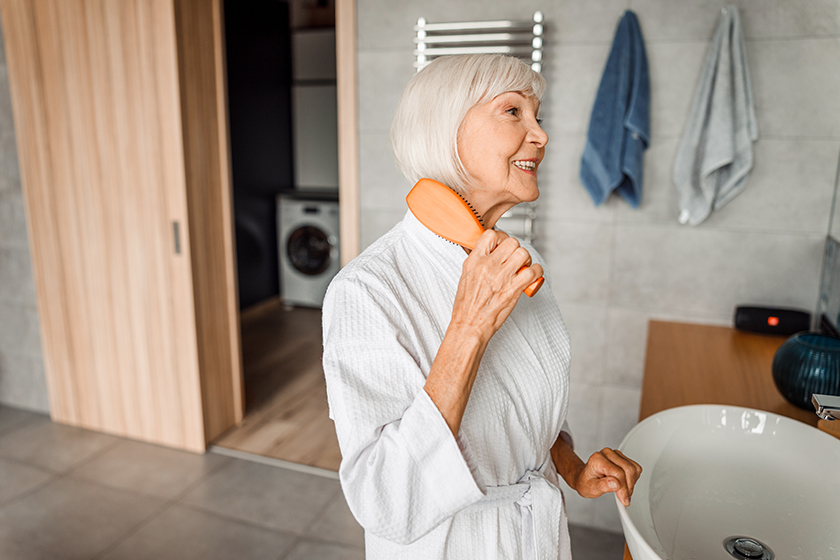 cheerful old woman brushing hair and smiling cheerful old woman brushing hair and smiling