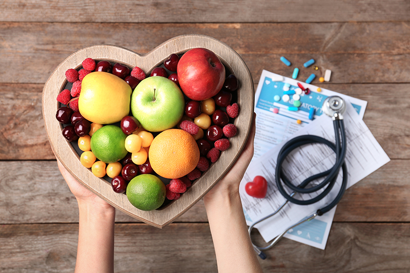 female doctor holding plate fresh fruits wooden table top view
