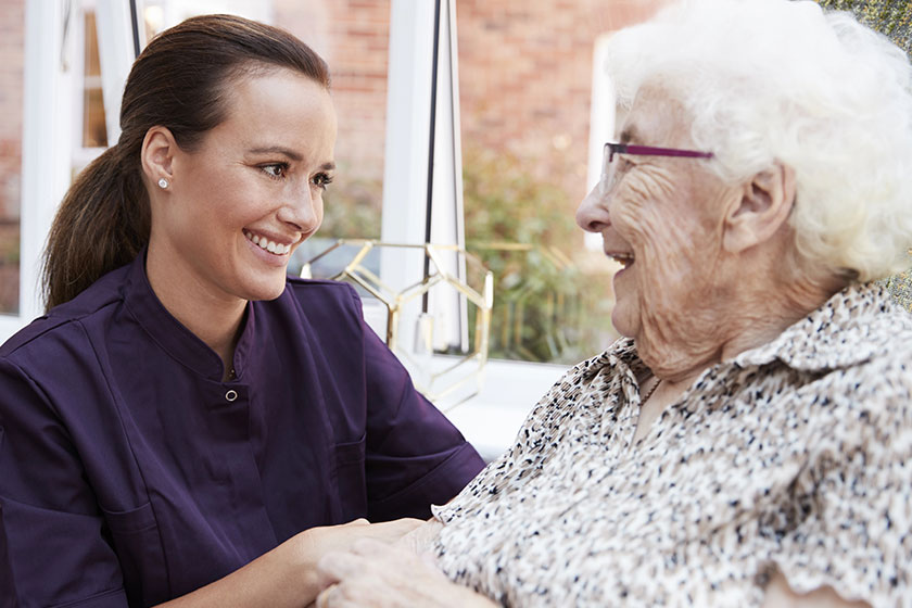 female resident sitting chair talking carer retirement home female resident sitting chair talking carer retirement home