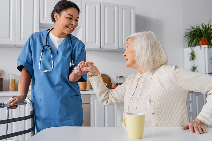 happy multiracial nurse blue uniform holding hand senior woman grey