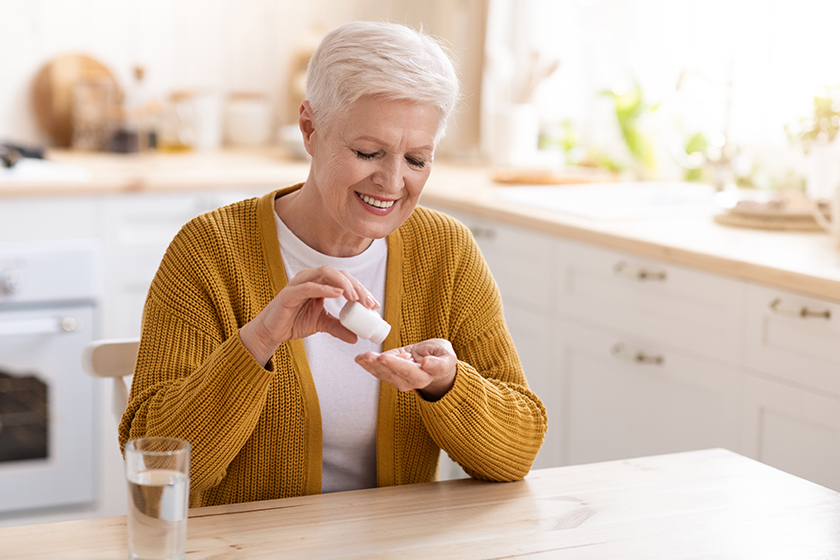 healthy old lady using supplements kitchen interior