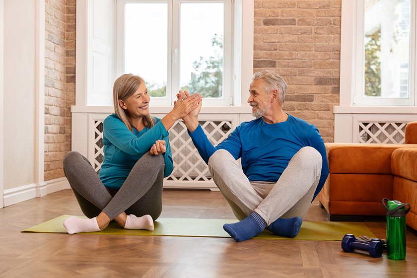 senior couple sitting yoga mat lotus position giving high five
