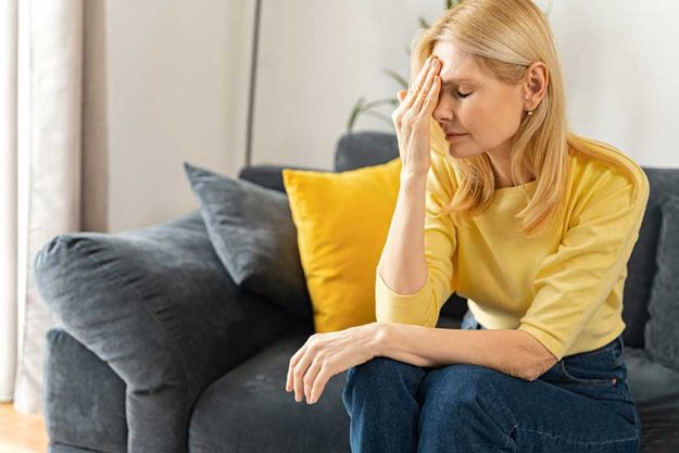 tired mature woman sitting on the sofa at home rubbing temple with suffering face feels tired mature woman sitting on the sofa at home rubbing temple with suffering face feels