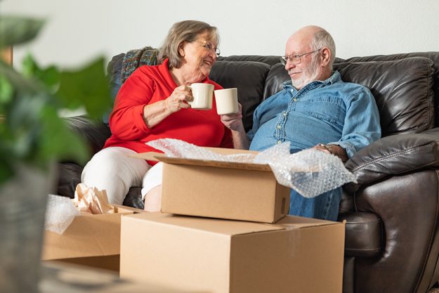 tired senior adult couple resting couch cups coffee surrounded moving