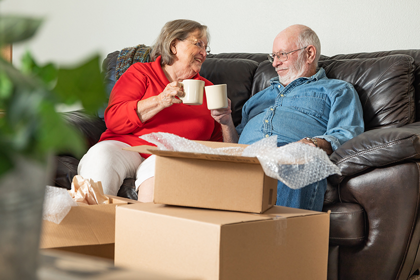 tired senior adult couple resting couch cups coffee surrounded moving