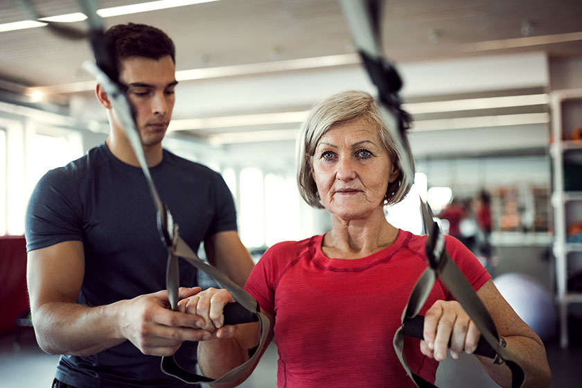 a senior woman in gym with a young trainer doing exercise with trx a senior woman in gym with a young trainer doing exercise with trx