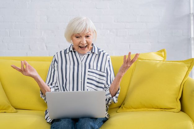 astonished woman using laptop living room
