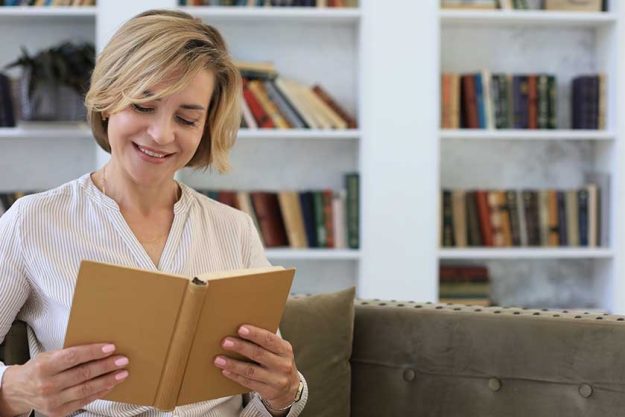 attractive middle aged woman enjoying reading book sitting sofa her