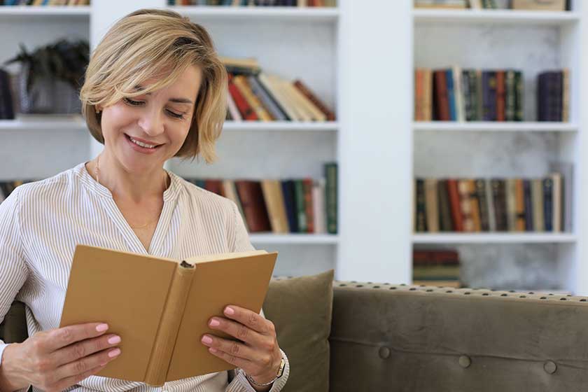 attractive middle aged woman enjoying reading book sitting sofa her