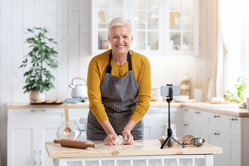 attractive senior lady cooking at home watching online class