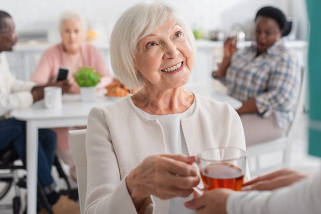 blurred nurse holding tea cheerful patient nursing home