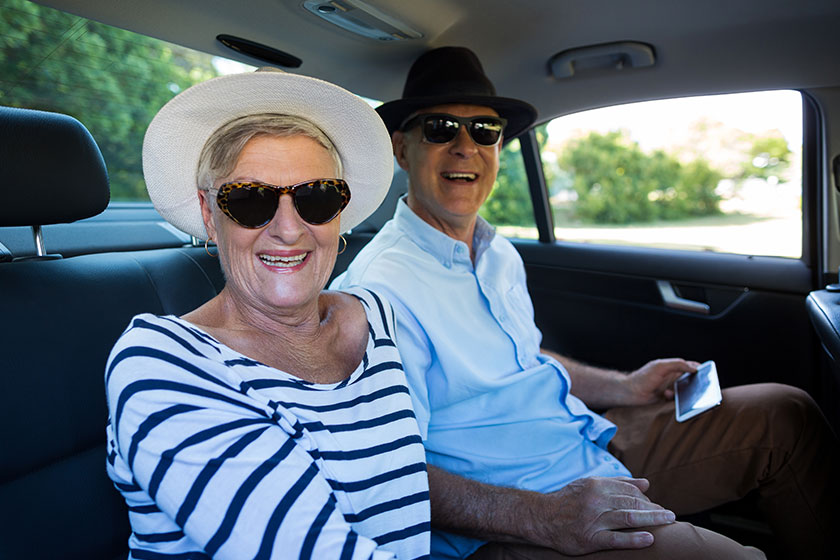 cheerful senior couple sitting in car