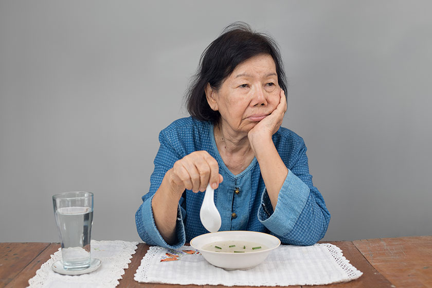 elderly asian woman bored with food