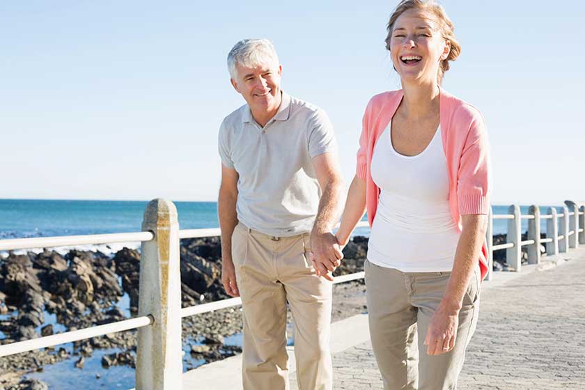 happy casual couple walking by the coast