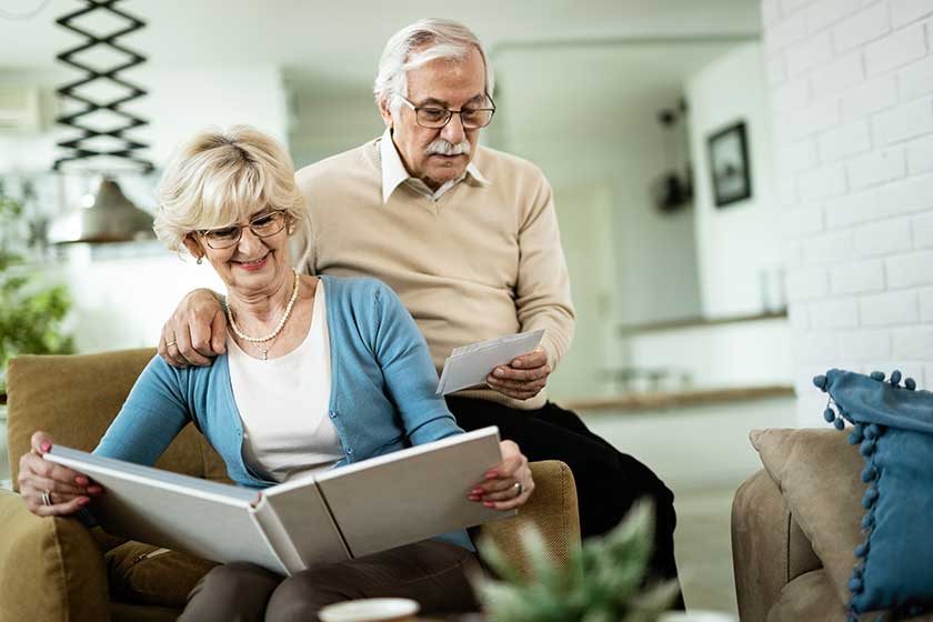 happy senior woman her husband looking old family photos while