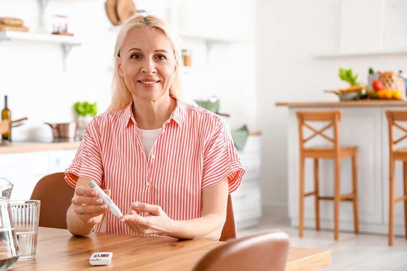 mature diabetic woman measuring blood sugar level lancet pen kitchen