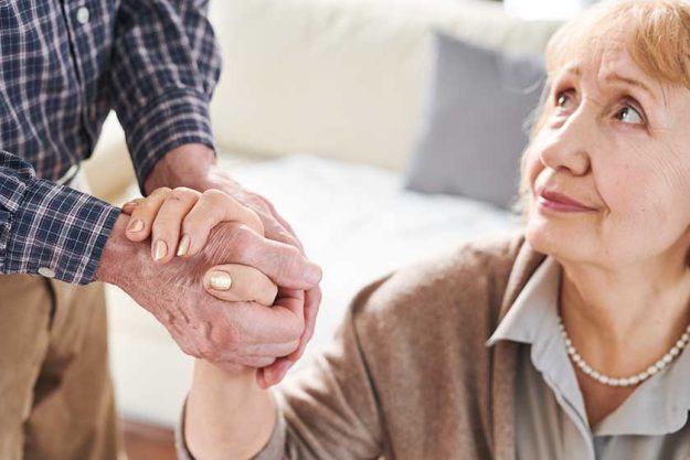 mature sick stressed woman looking her caregiver husband while holding