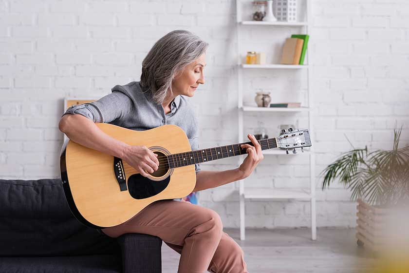 mature woman grey hair playing acoustic guitar living room mature woman grey hair playing acoustic guitar living room