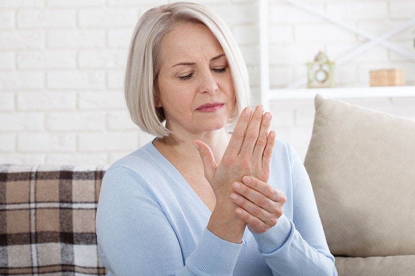 middle aged woman suffering from pain in hands woman massaging her arthritic hand and wrist