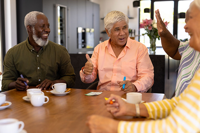 multiracial happy senior man showing thumbs while playing bingo friends