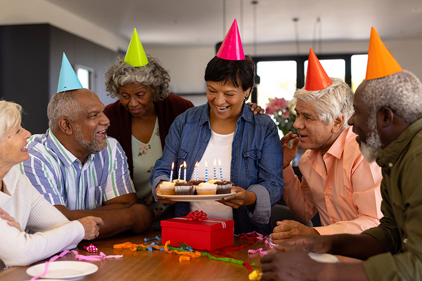 multiracial seniors wearing hats looking happy woman holding cupcakes birthday